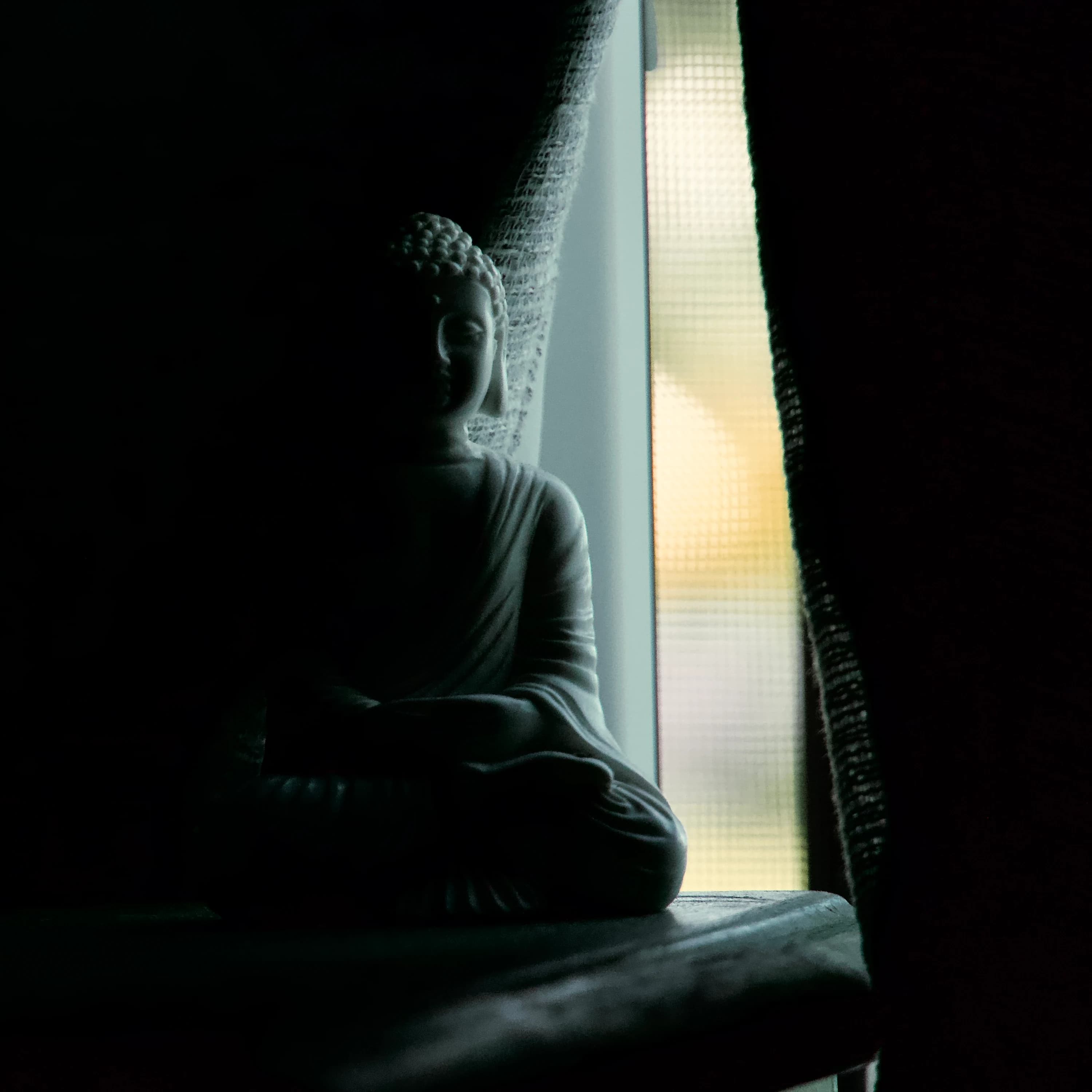 A Buddha figure illuminated by a small point of light.