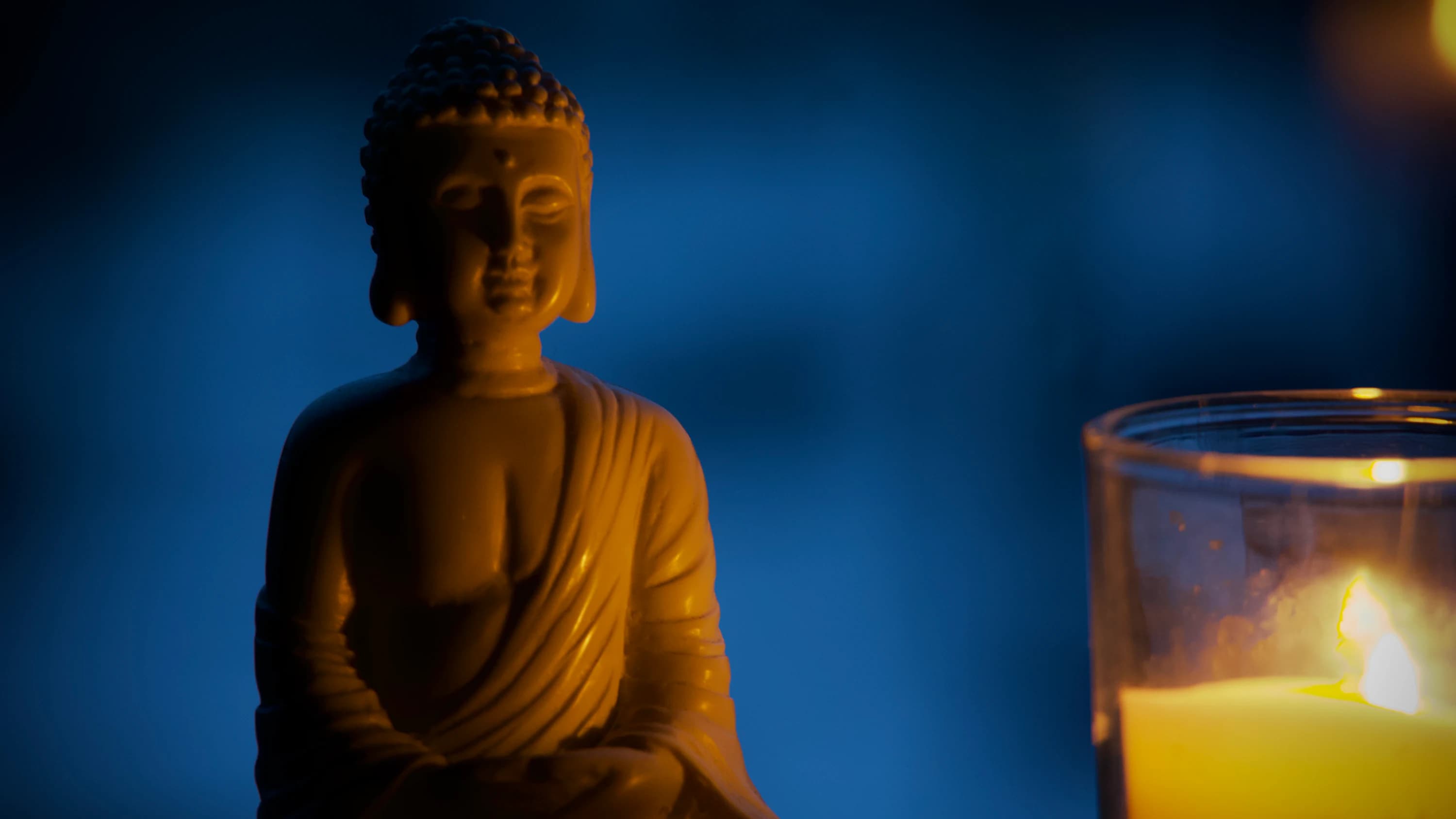 A Buddha figure illuminated by candlelight.