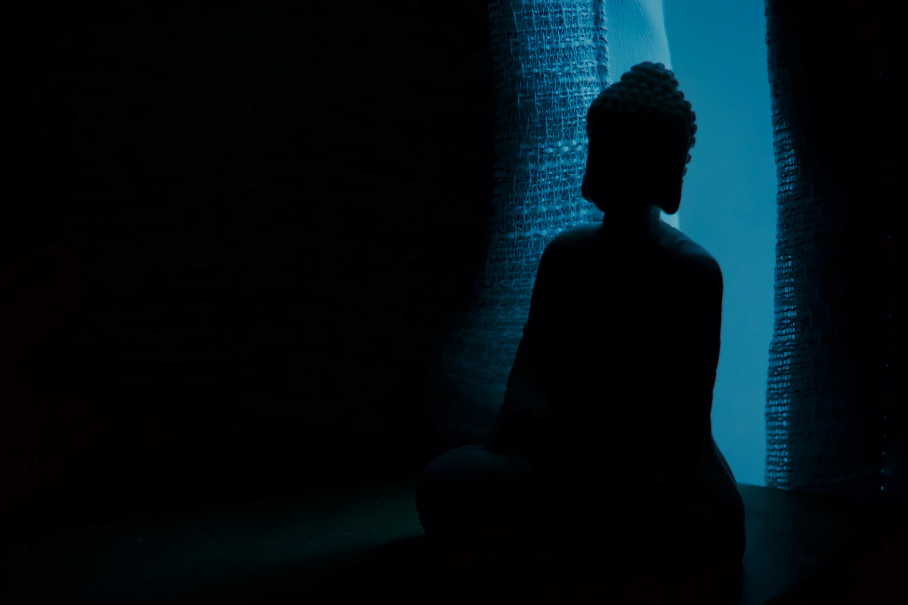 The silhouette of a Buddha figure.