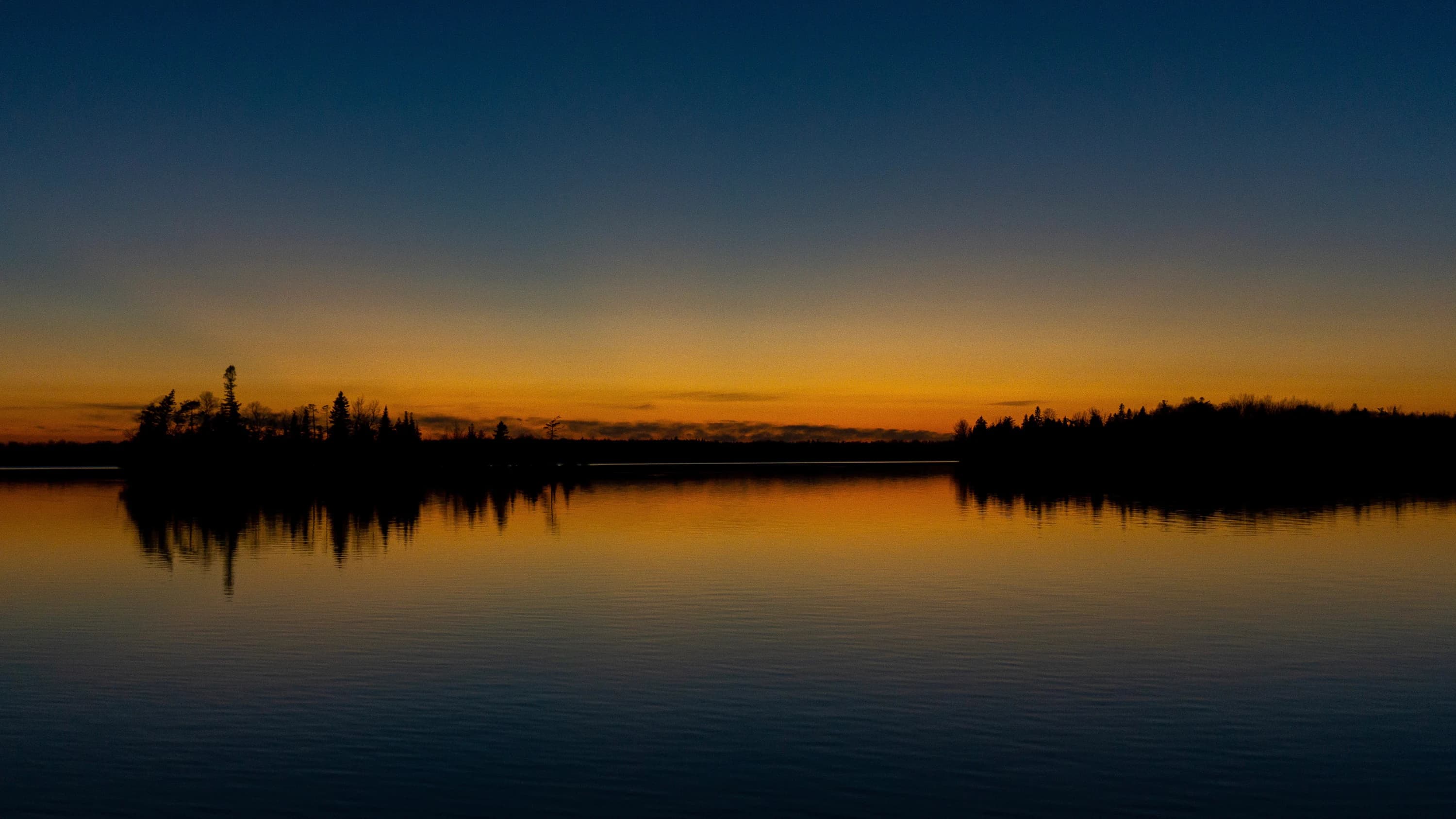 A sunrise reflected symmetrically across water.